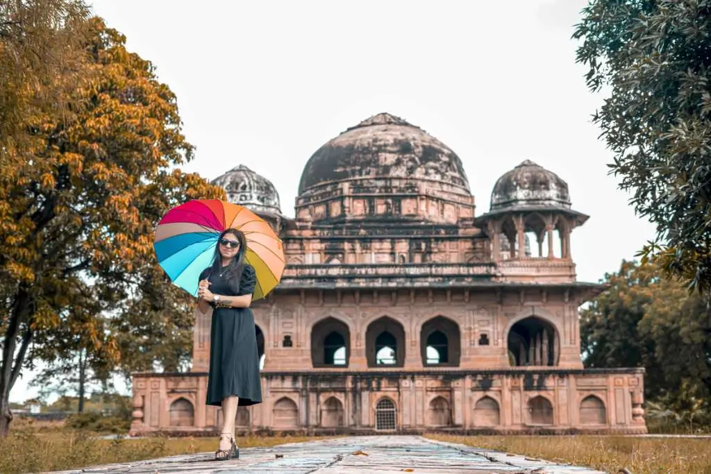 Stylish portrait photoshoot of woman holding colorful umbrella near historic monument